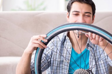 Evde bisiklet tamir eden genç bir adam.