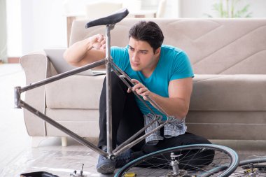 Evde bisiklet tamir eden genç bir adam.