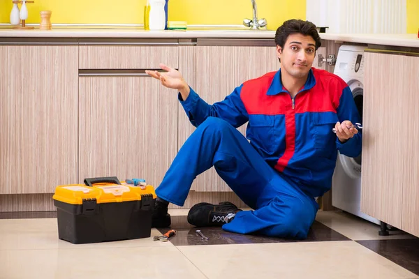 Reparador reparando lavadora en la cocina — Foto de Stock