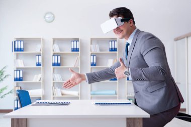 Ofiste sanal gerçeklik gözlüklü bir iş adamı var.