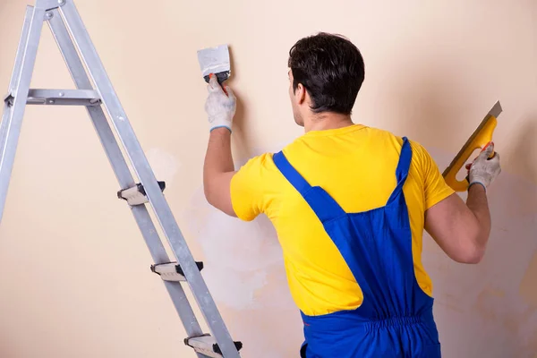 Empregado jovem empreiteiro aplicando gesso na parede — Fotografia de Stock