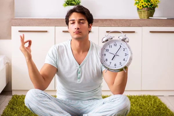Ung man gör yoga i sovrum i time management koncept — Stockfoto