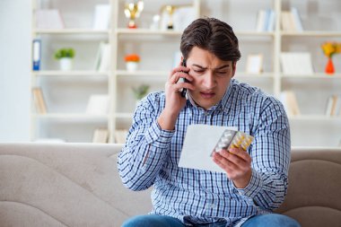 Kanepede ilaç ve reçeteyle oturan genç adam. 