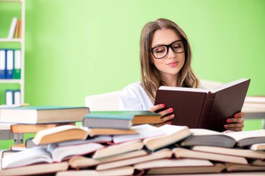 Sınavlara bir sürü kitapla hazırlanan genç kız öğrenci. 