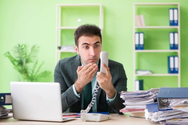İşadamı ofiste otururken aşırı çalışmaktan kızgın.