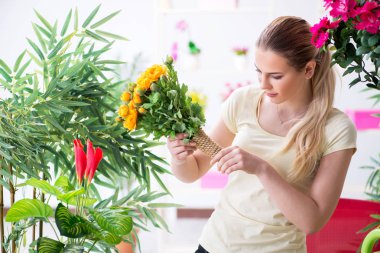 Bahçesinde çiçekleri sulayan genç bir kadın.