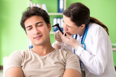 Female doctor checking patients ear during medical examination  clipart