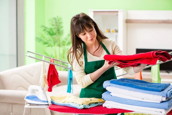 Mujer joven planchando ropa en casa — Foto de Stock