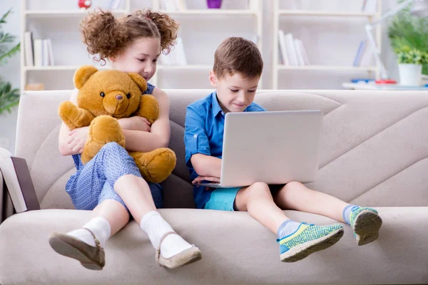 Due bambini seduti al computer portatile a casa — Foto Stock