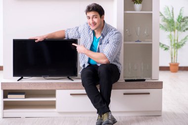 Genç adam evde televizyon izliyor.