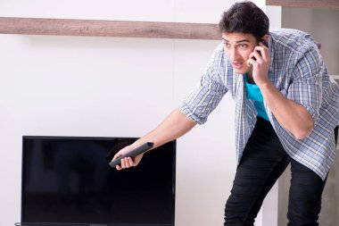 Bozuk televizyonu tamir etmeye çalışan adam