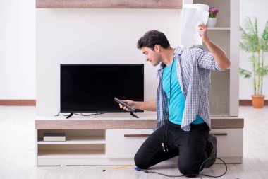 Bozuk televizyonu tamir etmeye çalışan adam