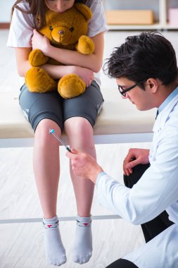 Doktor genç kızları çekiçle kontrol ediyor.