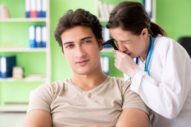 Tıbbi muayene sırasında kadın doktor hastaların kulaklarını kontrol ediyor. 