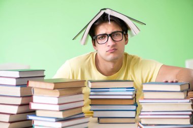 Sınavdan önce okumak için çok fazla kitabı olan öğrenci