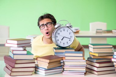 Sınavdan önce okumak için çok fazla kitabı olan öğrenci