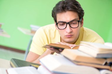 Sınavdan önce okumak için çok fazla kitabı olan öğrenci