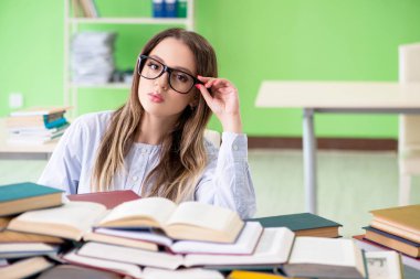 Sınavlara bir sürü kitapla hazırlanan genç kız öğrenci. 