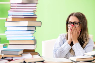 Sınavlara bir sürü kitapla hazırlanan genç kız öğrenci. 