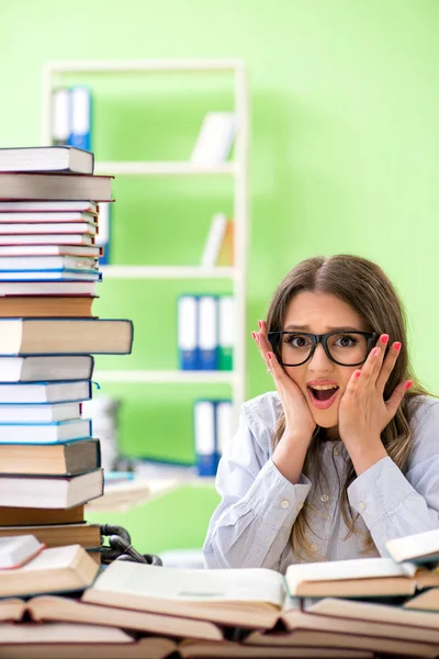 Jovem estudante se preparando para exames com muitos livros — Fotografia de Stock