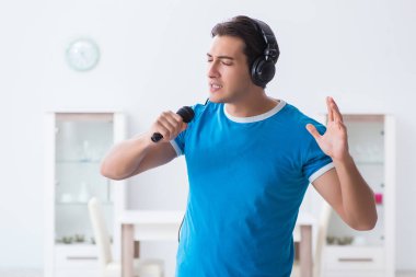 Genç yakışıklı adam evde karaoke yapıyor. 
