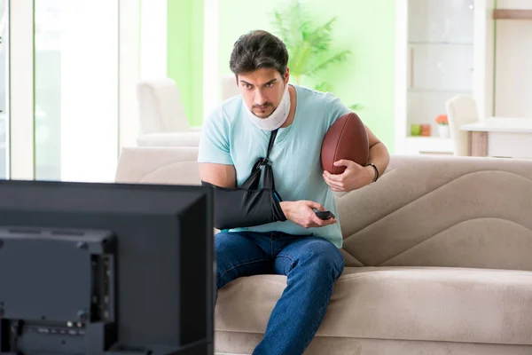 Hombre con lesión en el cuello y el brazo viendo fútbol americano en la televisión — Foto de Stock