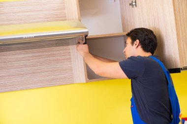 Genç müteahhit mutfak mobilyalarını monte ediyor.