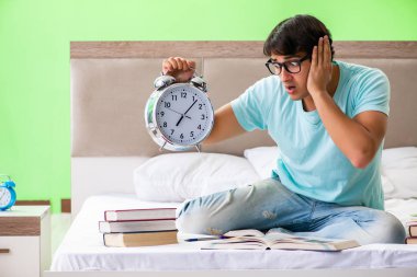 Sınavlara hazırlanan öğrenci yatak odasında oturuyor.