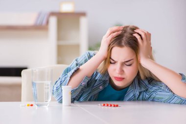 Kadın acıyla baş etmek için hap alıyor.