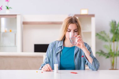 Kadın acıyla baş etmek için hap alıyor.