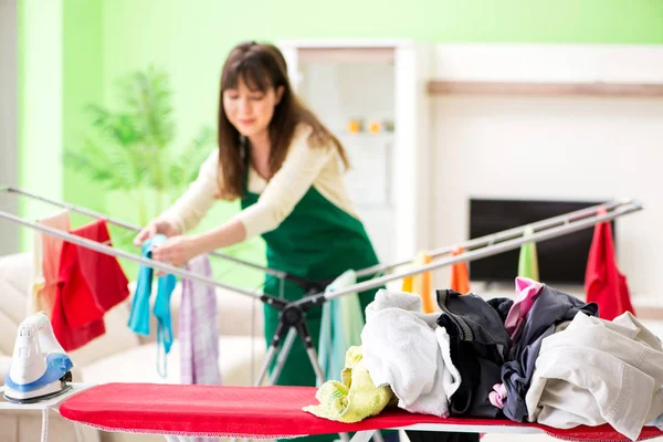 Mujer joven planchando ropa en casa — Foto de Stock