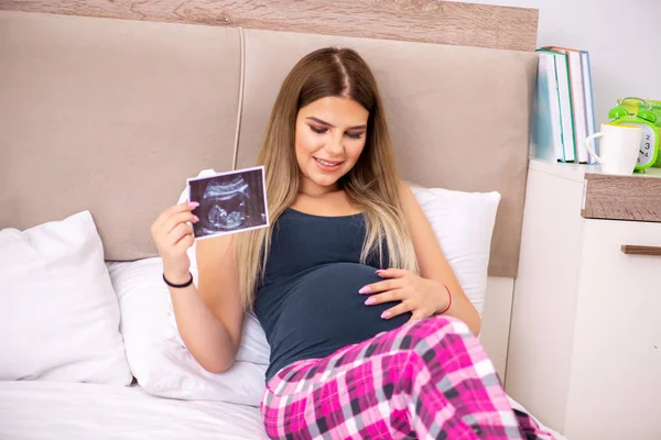 Счастливая молодая беременная женщина в постели — стоковое фото
