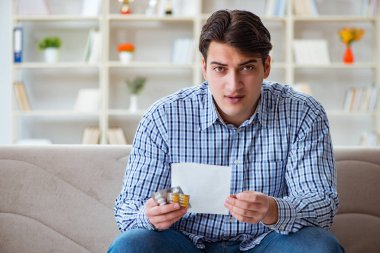 Kanepede ilaç ve reçeteyle oturan genç adam. 