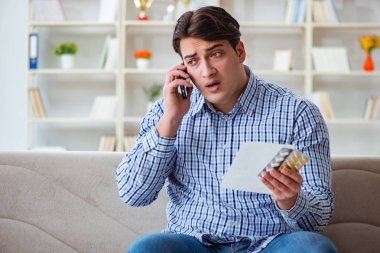 Kanepede ilaç ve reçeteyle oturan genç adam. 