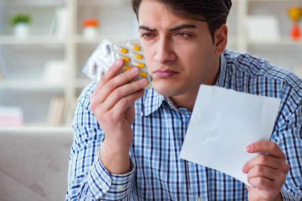 Joven sentado en el sofá con pastillas y prescripción — Foto de Stock