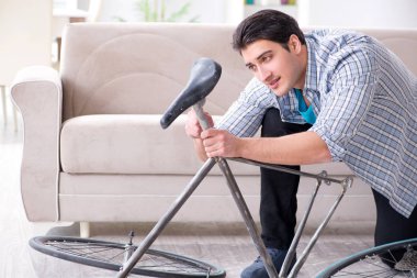 Evde bisiklet tamir eden genç bir adam.