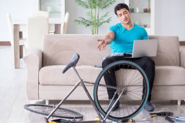 Evde bisiklet tamir eden genç bir adam.