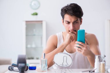 Genç yakışıklı adam aynaya bakıyor. 