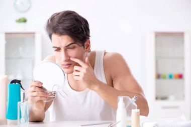 Genç yakışıklı adam aynaya bakıyor. 