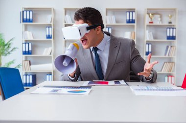 Ofiste sanal gerçeklik gözlüklü bir iş adamı var.