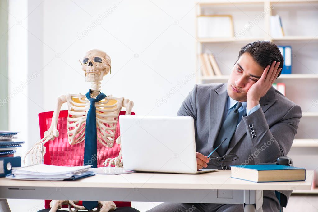 Businessman working with skeleton in office