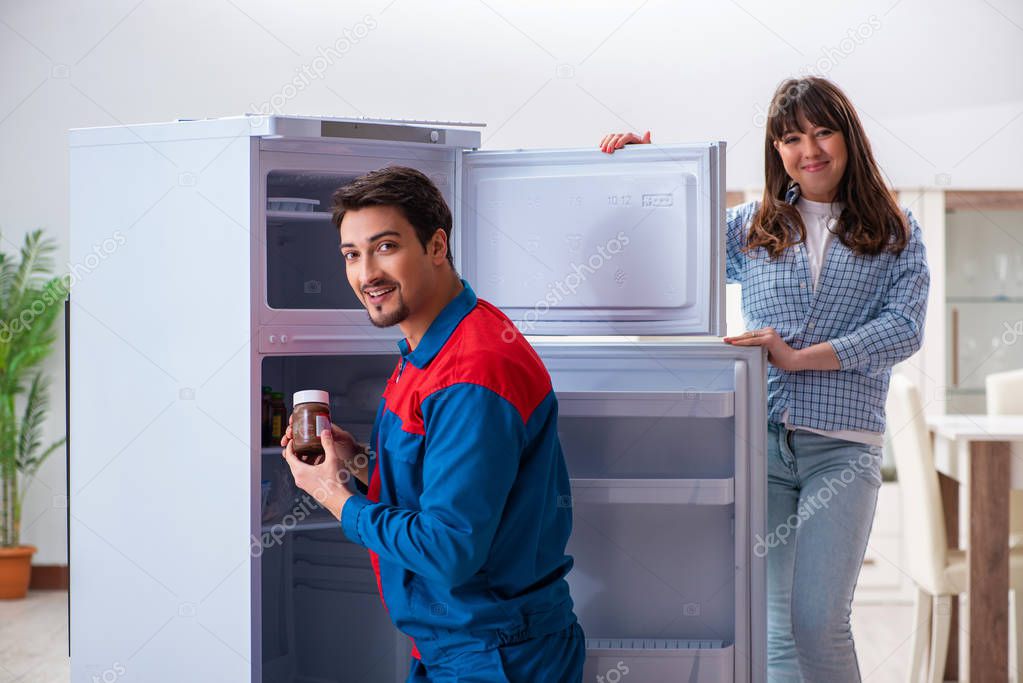 Man repairing fridge with customer