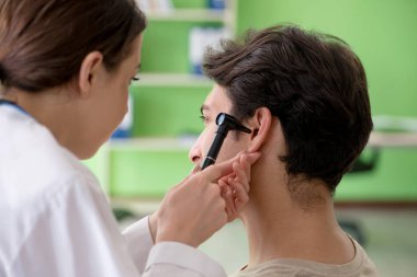 Tıbbi muayene sırasında kadın doktor hastaların kulaklarını kontrol ediyor. 