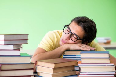 Sınavdan önce okumak için çok fazla kitabı olan öğrenci