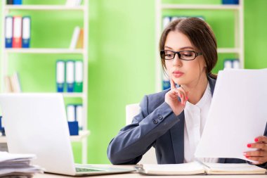 Genç bayan çalışan devam eden evrak işleriyle çok meşgul.