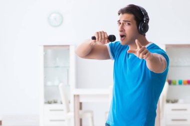 Genç yakışıklı adam evde karaoke yapıyor. 