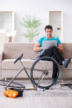 Evde bisiklet tamir eden genç bir adam.