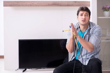 Bozuk televizyonu tamir etmeye çalışan adam