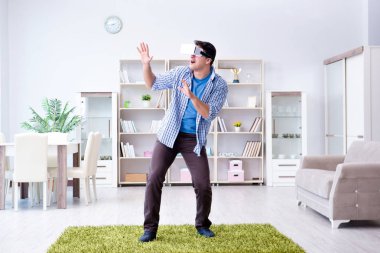 Evde sanal gerçeklik gözlüklü bir adam oynuyor.