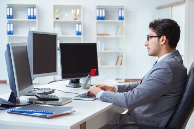 Birçok ekranın önünde oturan bir iş adamı